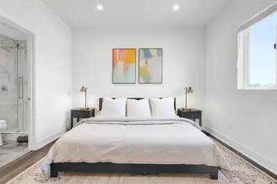 a white bedroom with a large bed and two lamps at Luxe Townhouse Near Downtown LA in Los Angeles