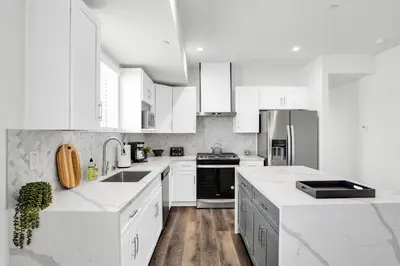 a white kitchen with white appliances and white cabinets at Spectacular Rooftop View House in Los Angeles
