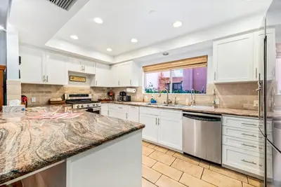 a kitchen with white cabinets and a marble counter top at House on the canal in Venice in Los Angeles