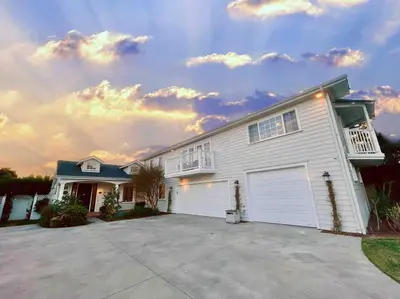 a large white house with a large driveway at New Charming Spacious Disneyland Pool Home in Garden Grove