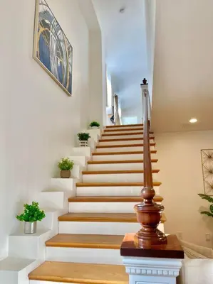 a staircase in a home with white steps and plants at New Charming Spacious Disneyland Pool Home in Garden Grove