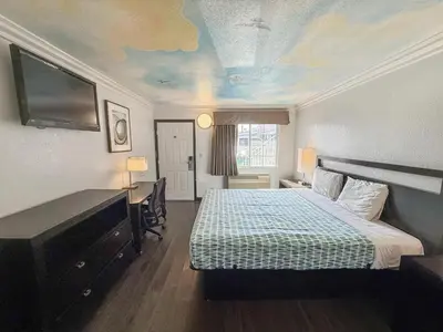 a hotel room with a bed and a painting on the ceiling at Super 7 Motel - Anaheim Packing District & Disneyland in Anaheim