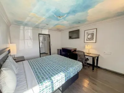 a bedroom with a bed and a desk and a ceiling at Super 7 Motel - Anaheim Packing District & Disneyland in Anaheim