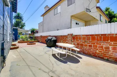 a table and bench in front of a brick wall at 2 Mi to Ocean Long Beach Home with Gas Grill! in Long Beach