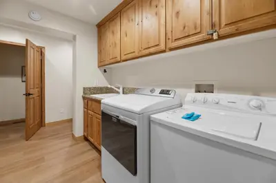 a kitchen with a washer and dryer and wooden cabinets at Arctic Wolf at Summit Base - 4 Bedroom log cabin at the base of Snow Summit in Big Bear Lake