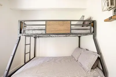 a bunk bed in a small room with a ladder at Sprocket Hollow Treetop A-Frame Log Cabin in Cedar Glen