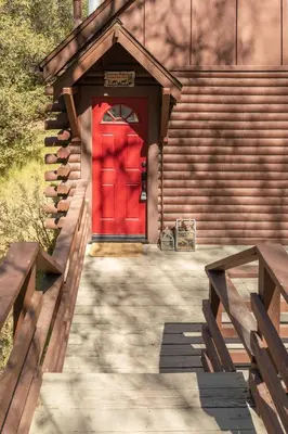 a red door of a building with stairs and benches at Sprocket Hollow Treetop A-Frame Log Cabin in Cedar Glen
