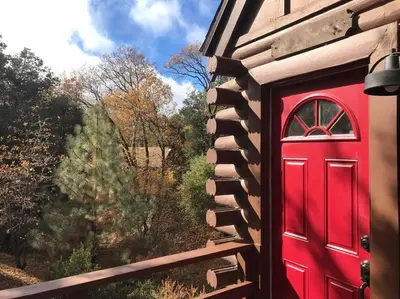 a red door on the side of a house at Sprocket Hollow Treetop A-Frame Log Cabin in Cedar Glen