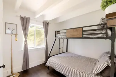 a bedroom with two bunk beds and a window at Sprocket Hollow Treetop A-Frame Log Cabin in Cedar Glen