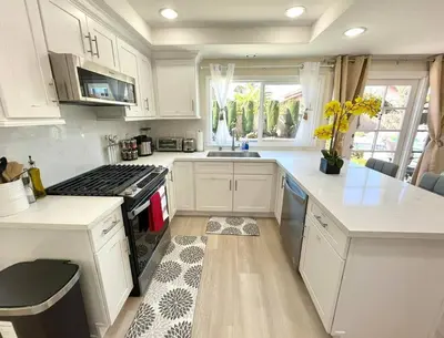 a kitchen with white cabinets and a stove top oven at Family Paradise near Disneyland with Sparkling Pool in Del Prado Bolsa