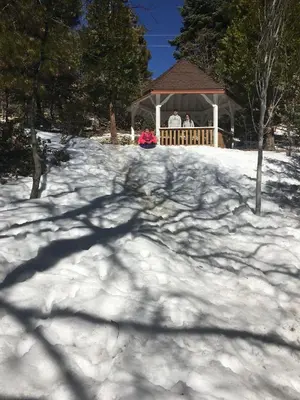 a snow covered yard with a gazebo with two people at Gingerbread Gardens in Twin Peaks