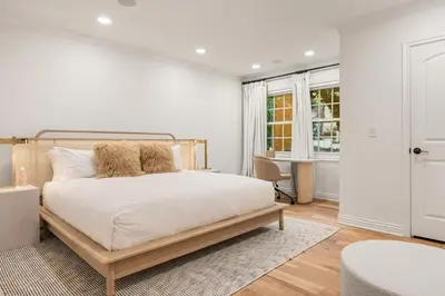 a bedroom with a large bed with white walls and wooden floors at Belmont Beverly Hills by Stay Awhile Villas in Los Angeles