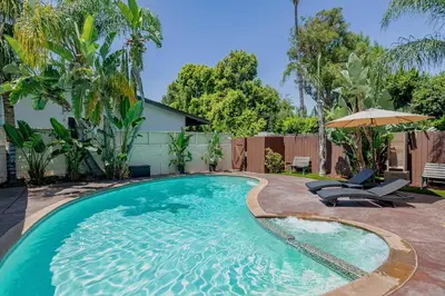 a swimming pool with two chairs and an umbrella at Cozy Home with Pool and Jacuzzi Minutes from Universal Studios in Los Angeles