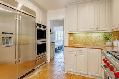 a kitchen with white cabinets and a stainless steel refrigerator at Cozy Home with Pool and Jacuzzi Minutes from Universal Studios in Los Angeles