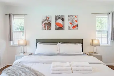 a bedroom with a white bed with two windows at Cozy Home with Pool and Jacuzzi Minutes from Universal Studios in Los Angeles
