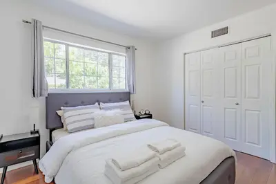 a white bedroom with a large bed with towels on it at Cozy Home with Pool and Jacuzzi Minutes from Universal Studios in Los Angeles