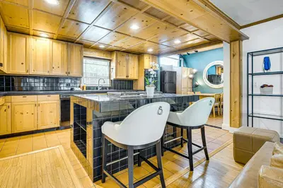 a kitchen with wooden cabinets and white chairs at Walk to Abbot Kinney Tranquil Cottage in Venice! in Los Angeles