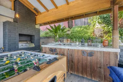 an outdoor kitchen with a ping pong table in a backyard at Middlebury Heights with Pool in Los Angeles