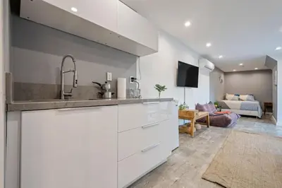 a kitchen with white cabinets and a living room at Middlebury Heights with Pool in Los Angeles