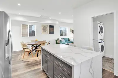 a kitchen and living room with a table and a refrigerator at Fresh & New Downtown LA Condo! in Los Angeles