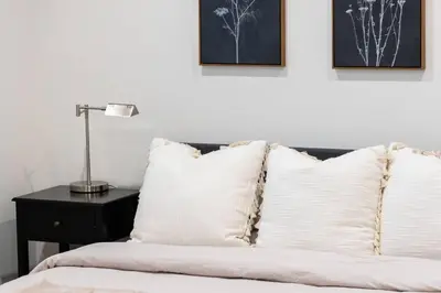 a bed with white pillows and a lamp on a table at Fresh & New Downtown LA Condo! in Los Angeles