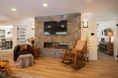 a living room with a stone fireplace with a television at 37 - Foxy Farm Ranch home in Big Bear Lake
