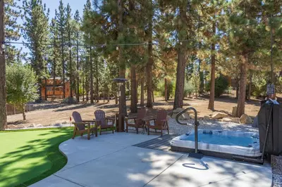 a backyard with a hot tub and a table and chairs at 37 - Foxy Farm Ranch home in Big Bear Lake