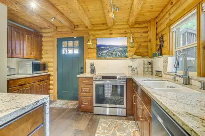 a kitchen with wooden cabinets and a large window at Cabin about 1 Mi to Lake Gregory and Hiking! in Crestline