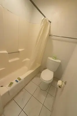 a white bathroom with a toilet and a bath tub at Casa Blanca Hotel - Azusa, Los Angeles in Azusa