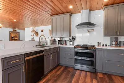 a kitchen with gray cabinets and a stove at The Lazy Bear - Indulge in breathtaking views of the expansive lake from this charming cabin. in Fawnskin