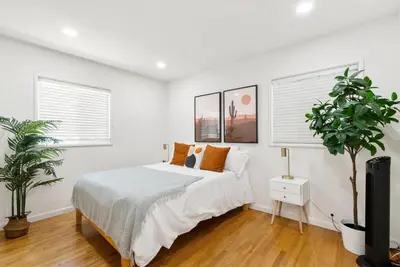 a white bedroom with a bed and a plant at Spacious 3BR Home Near Disneyland & Knotts Berry Farm in Fullerton