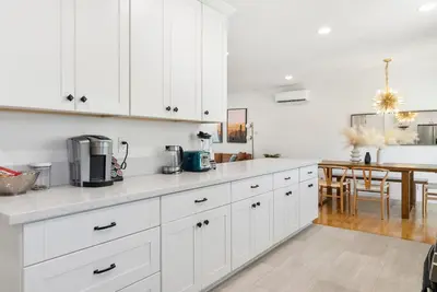 a kitchen with white cabinets and a dining room at Spacious 3BR Home Near Disneyland & Knotts Berry Farm in Fullerton