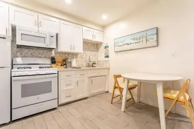 a kitchen with white cabinets and a table and a microwave at Walk 2 Beach, Parking, AC, WD,15min2LAX,Remodel in Manhattan Beach