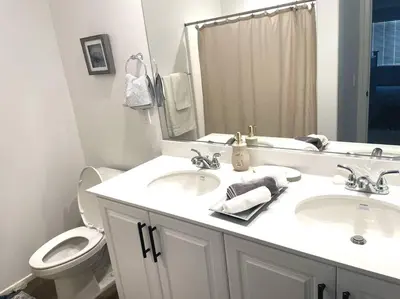 a bathroom with two sinks and a toilet and a mirror at Modern Desert Gem, Boho Retreat 2 Living Rooms in Hesperia