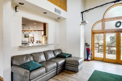 a living room with a leather couch and a mirror at Simple Life Ranch with Hot Tub and Sauna in Keene! in Keene
