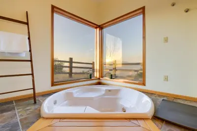 a large white tub in a room with windows at Simple Life Ranch with Hot Tub and Sauna in Keene! in Keene