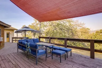 a deck with blue chairs and a table and an umbrella at Simple Life Ranch with Hot Tub and Sauna in Keene! in Keene