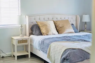 a bedroom with a white bed with blue sheets and pillows at Great Location Oasis w Huge Backyard Near DTLA ,USC ,Ktown in Los Angeles