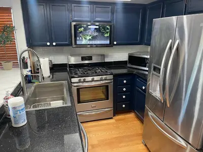 a kitchen with blue cabinets and a stainless steel refrigerator at Central LA GATED Community 4 beds home in Commerce