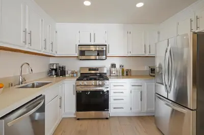 a kitchen with white cabinets and a stainless steel refrigerator at Aquamarine Best View in Malibu by Stay Awhile Villas in Malibu Beach