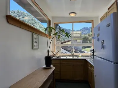 a kitchen with a refrigerator and a table and a window at Topanga Panoramic View Loft with Trails & Creeks in Topanga
