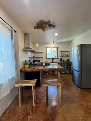 a kitchen with a refrigerator and a table and two stools at Vacation House in Ontario - Two Bedroom Brand New and Hand Made Furniture in Ontario