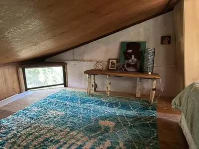 an attic room with a table and a rug at Topanga Wonderland Cottage in Topanga