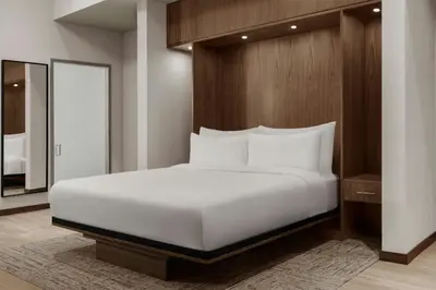 a bedroom with a large white bed and a mirror at AC Hotel by Marriott Pasadena in Pasadena