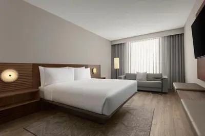 a bedroom with a large white bed and a couch at AC Hotel by Marriott Pasadena in Pasadena