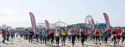 a large group of people running on the beach at The Pearl Coast - Rooftop Pool, Gym Luxurious 2BR Santa Monica in Los Angeles