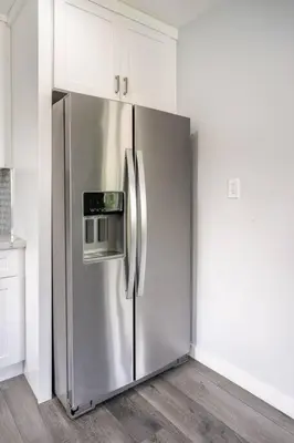 a stainless steel refrigerator in a kitchen with white cabinets at Adorable 2BR-2BA House with EV & Free Parking and Family Friendly in Los Angeles in Los Angeles