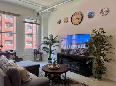 a living room with a large television and a clock on the wall at Iconic Heart of DTLA Loft with Rooftop Pool Jacuzzi Gym in Los Angeles