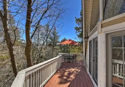 a porch of a house with a table and an umbrella at Whispering Pines A-Frame, Pool Table, 2 Patios! in Lake Arrowhead