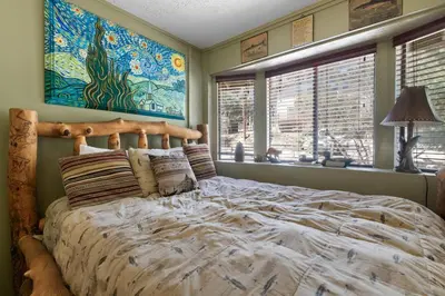 a bedroom with a large bed and a painting on the wall at Smo Haus- Located in the quiet area of Big Bear City, with mountain views. in Big Bear City